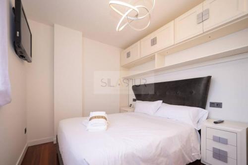 - une chambre avec un lit blanc et une tête de lit noire dans l'établissement Deva Apartamento, à Soto del Barco