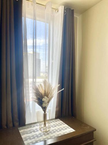 a vase with flowers on a table in front of a window at Sunset View 1-BR Unit at Centrio Tower beside Ayala Mall Downtown CDO in Cagayan de Oro