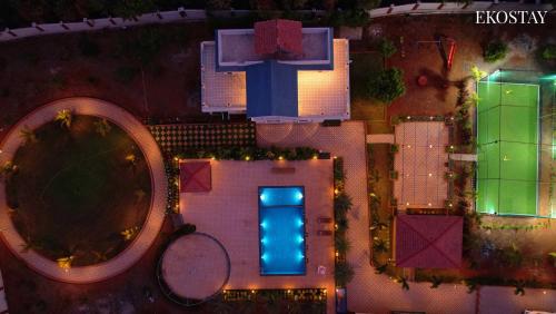 an overhead view of a tennis court with two tennis rackets at Ekostay Gold Palm Estate I Cricket Turf I Rain Dance I 2 Acre Property in Karjat