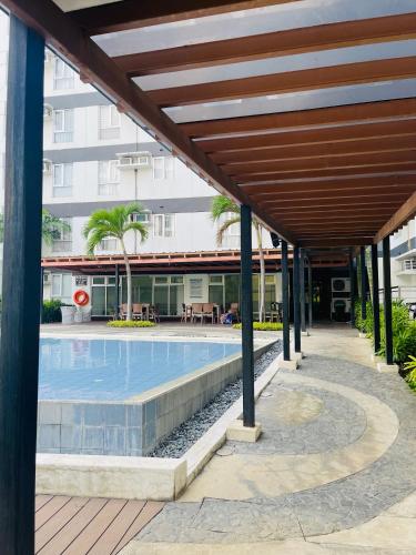 an outdoor swimming pool with a wooden pergola at Sunset View 1-BR Unit at Centrio Tower beside Ayala Mall Downtown CDO in Cagayan de Oro