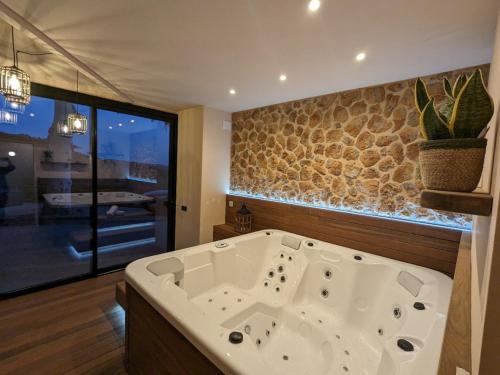 a large white tub in a bathroom with a stone wall at Masia d'Amer - Complex rural amb encant in Amer