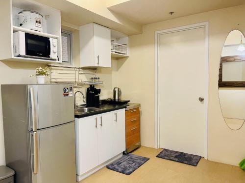 a kitchen with white cabinets and a refrigerator at Sunset View 1-BR Unit at Centrio Tower beside Ayala Mall Downtown CDO in Cagayan de Oro