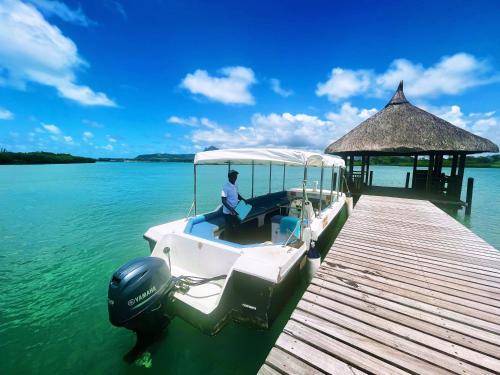 a man sitting on a boat at a dock at Villa Shanti Anahita in Grande Rivière Sud Est