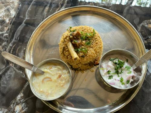 a plate of food with a sandwich and dipping sauce at Greenwoods Nature Camp in Mudumalai National Park