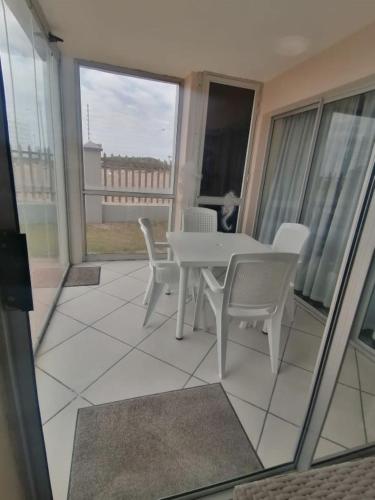 a white table and chairs on a balcony with windows at Modern Seaview Apartment in Summerstrand