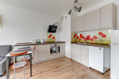 una cocina con armarios blancos, una mesa y una barra en Spektrum by Grand Apartments en Gdansk