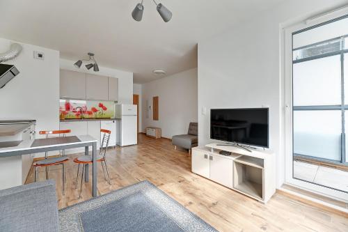 cocina y sala de estar con mesa y TV en Spektrum by Grand Apartments en Gdansk