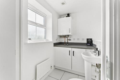a white bathroom with a sink and a toilet at Captivating 4 bed House - Parking - Sleeps 14 in Bristol
