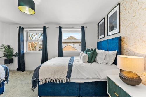 a bedroom with a blue bed and two windows at Captivating 4 bed House - Parking - Sleeps 14 in Bristol