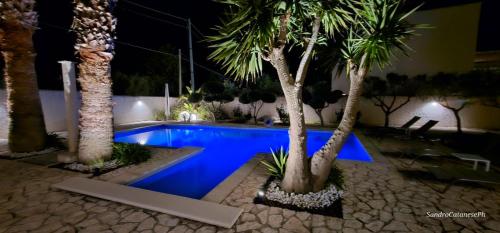 a pool with palm trees in a resort at night at 5 elementi in Porto Empedocle