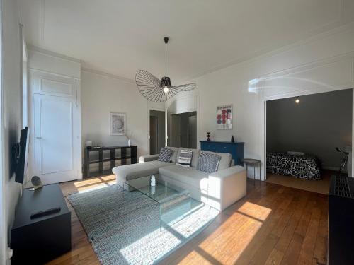 uma sala de estar com um sofá branco e uma mesa de vidro em Suite Lavani em Lyon