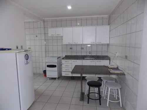 uma cozinha com electrodomésticos brancos, uma mesa e bancos em Hotel Rota do Pantanal em Presidente Prudente