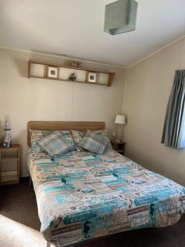 a bedroom with a bed with a comforter and pillows at Willows Way Newquay Holiday Park in Newquay