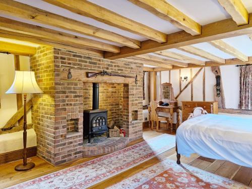 Walnut Barn - Horsham في هورشام: غرفة نوم مع موقد من الطوب وسرير
