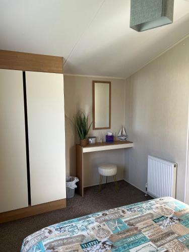 a bedroom with a bed and a desk and a mirror at Willows Way Newquay Holiday Park in Newquay