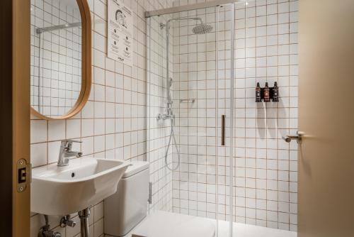 un bagno piastrellato bianco con lavandino e doccia di BYPILLOW Ramblas a Barcellona
