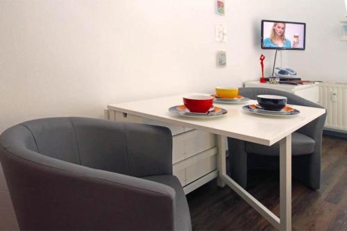 uma mesa com duas tigelas com uma cadeira em Yachthafenresidenz-Wohnung-8106-9412 em Kühlungsborn