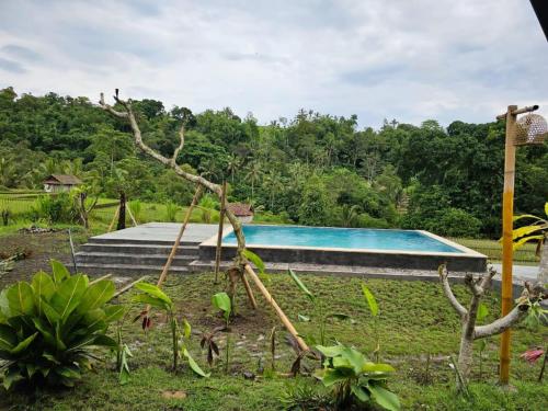una piscina en un jardín con árboles en el fondo en UmaUthu Bali, en Tabanan