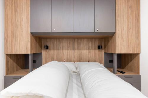 Schlafzimmer mit einem Bett mit weißer Bettwäsche und Schränken in der Unterkunft Dolomiti Haus - Immerso nelle Dolomiti in Tesero