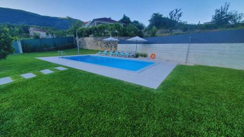 - une piscine dans une cour avec une pelouse verdoyante dans l'établissement Casa do Tourão - Ponte de Lima, à Ponte de Lima