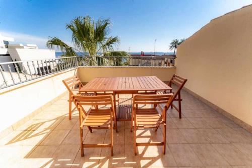 une table et des chaises en bois sur un balcon dans l'établissement Adosado con vistas al Mar Menor y parking, à Santiago de la Ribera