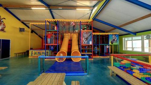 una sala de juegos para niños con un parque infantil con tobogán en Chalet NiNo en Raalte