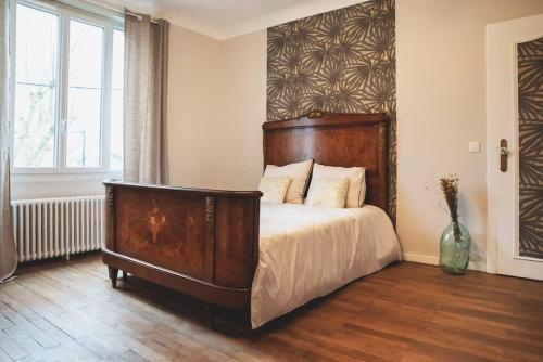 a bedroom with a large bed with a wooden headboard at Le Bédier in Angers