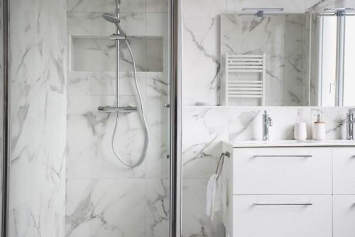 a white bathroom with a shower and a sink at Le Bédier in Angers