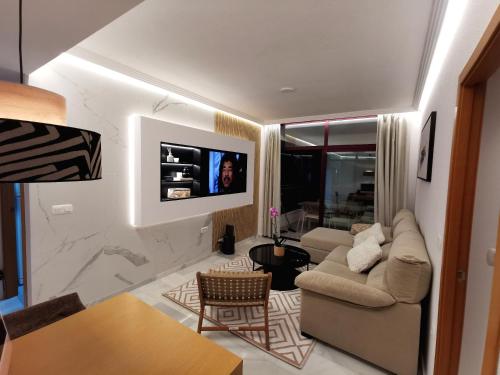 ein Wohnzimmer mit einem Sofa und einem TV an der Wand in der Unterkunft PANORAMIC in Benidorm