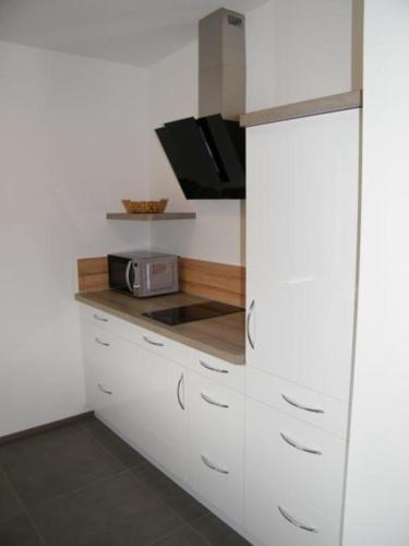 a kitchen with white cabinets and a microwave at Haus Schloßbergblick in Leutschach