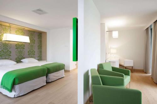 a bedroom with a green bed and a green chair at NH Amsterdam Noord in Amsterdam