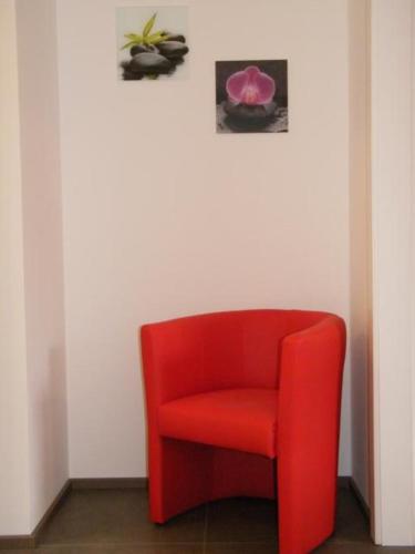 a red chair in a room with two pictures on the wall at Haus Schloßbergblick in Leutschach