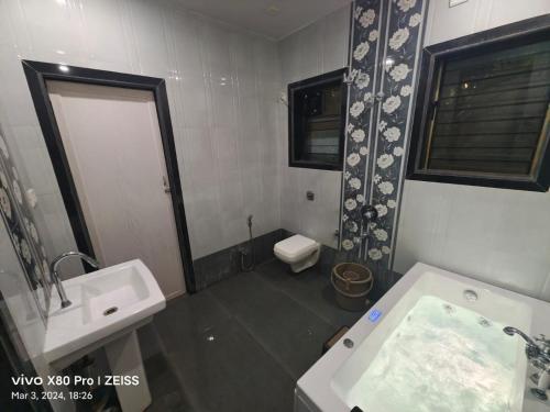 een badkamer met een bad, een wastafel en een toilet bij Casa Coconut in Revadanda