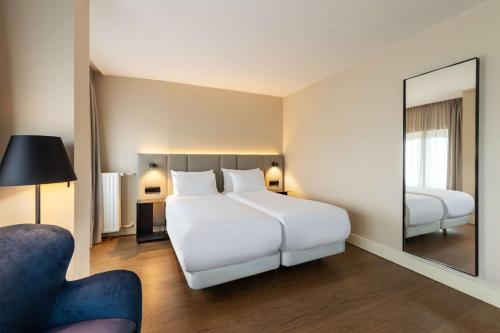 a bedroom with a large white bed and a mirror at NH Amsterdam Schiller in Amsterdam