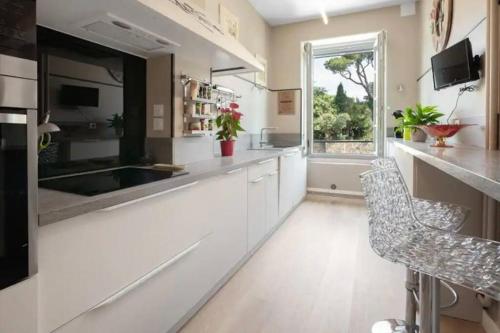 une grande cuisine avec des armoires blanches et une fenêtre dans l'établissement La Majestueuse Cité, à Carcassonne