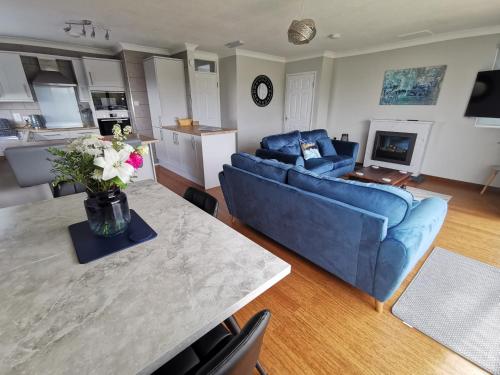 a living room with a blue couch and a table with flowers at River View - Norfolk Broads in Brundall