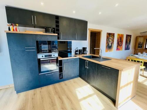 Il comprend une cuisine avec des placards bleus et du parquet. dans l'établissement Appartement La Galerie de Mémé, à Gérardmer