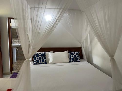Un dormitorio con una cama blanca con cortinas. en New Bimal Villa, en Bentota