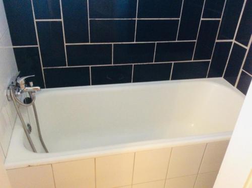 a white bath tub with black tiles on the wall at Apartment Sirius A in center of CB. in České Budějovice