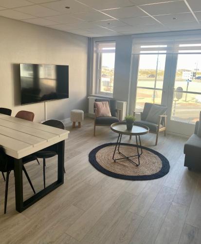 a living room with a table and chairs and a couch at Residence Le Mistral in Noordwijk aan Zee