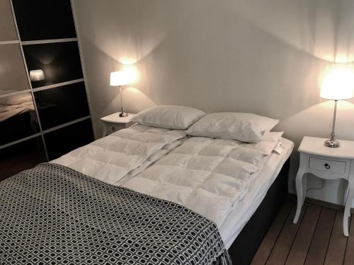 a bedroom with a bed with two tables and two lamps at Svolvær Havn Apartments in Svolvær