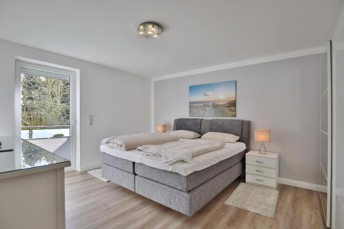 een witte slaapkamer met een bed en een raam bij Appartemenhaus Linda-Lu Appartementhaus Linda-Lu Appartement 1 in Scharbeutz