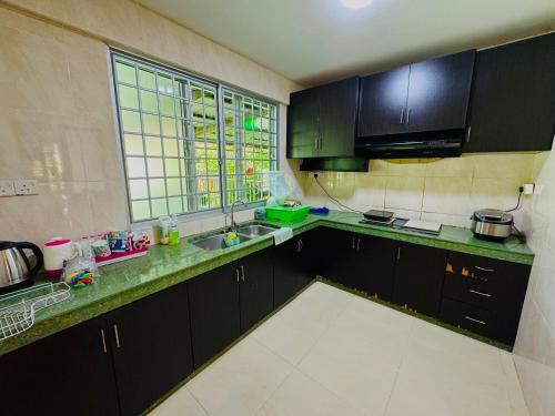 a kitchen with black cabinets and a sink and a window at HmAirbnb@Two in Sibu