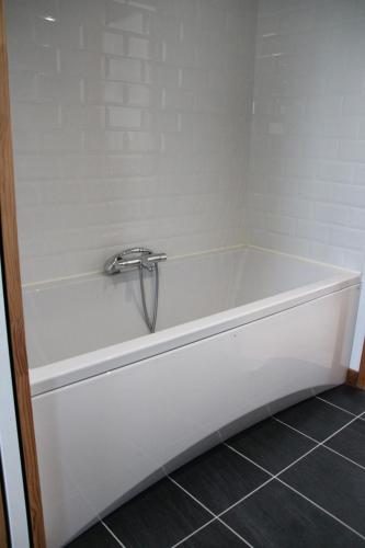 La salle de bains est pourvue d'une baignoire blanche et de carrelage. dans l'établissement Ty Laouen - Maison proche plage et centre-ville, à Roscoff