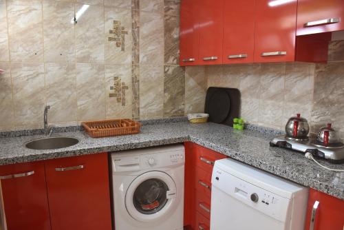 a kitchen with red cabinets and a washing machine at MELLES OTEL in Antalya