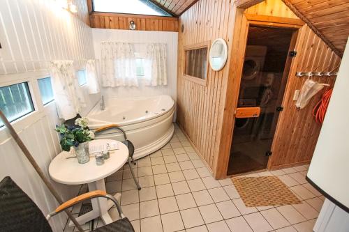 y baño con bañera, mesa y lavamanos. en Uniquely located wooden cottage by the sea - SJ1 en Harboør