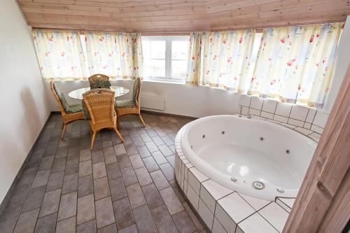 La salle de bains est pourvue d'une baignoire, d'une table et de chaises. dans l'établissement Cottage with wood-burning stove by the sea - SJ760, à Harboør