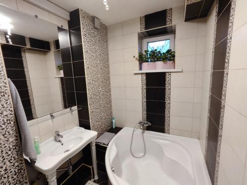 uma casa de banho com uma banheira branca e um lavatório. em Gold Rose Apartament em Chisinau