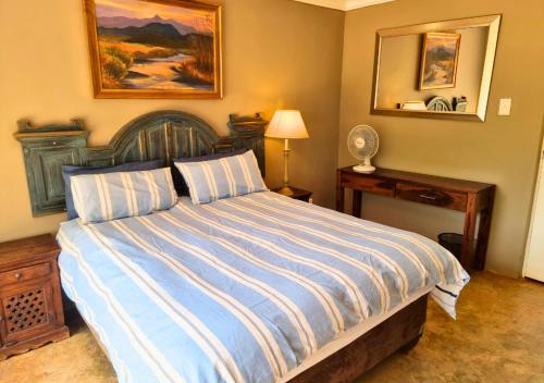 a bedroom with a bed with a blue and white comforter at Imbabali Retreat & Venue in Magaliesburg