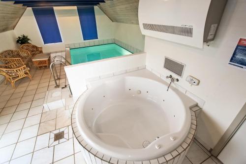 uma grande banheira num quarto com piscina em Thatched house with spa and pool by the sea - SJ67 em Harboør